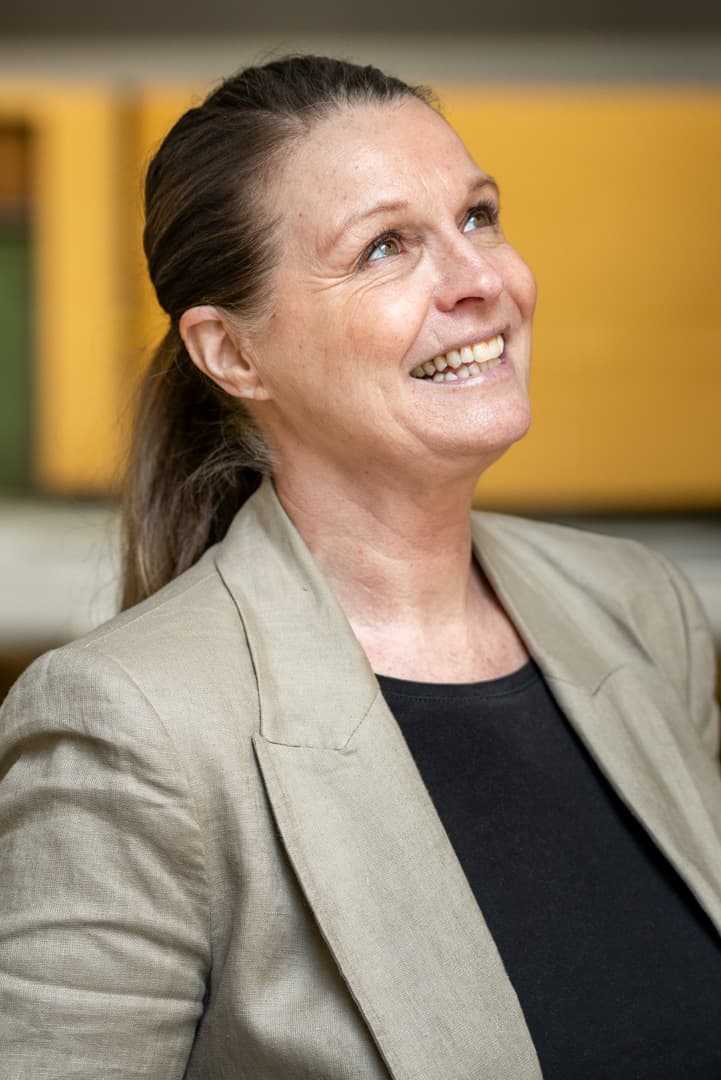 Anneli ser skrått opp i luften og smiler.